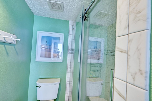 full bath featuring toilet, a stall shower, and a textured ceiling