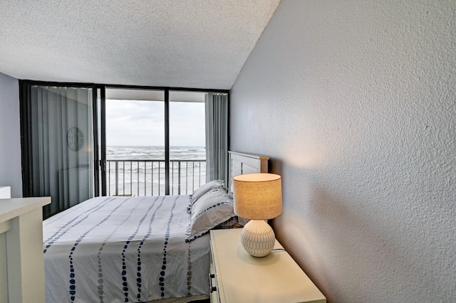 bedroom with expansive windows, a textured ceiling, access to outside, and a textured wall