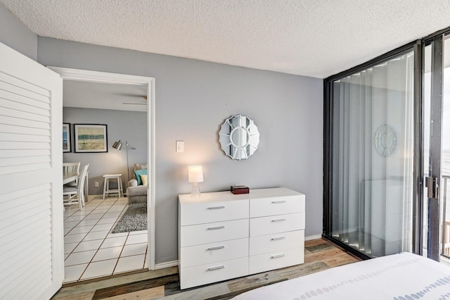 bedroom featuring light wood-style flooring, baseboards, and a textured ceiling