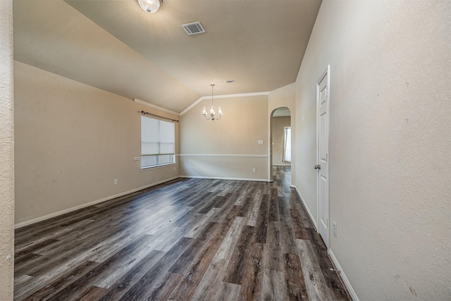 spare room featuring visible vents, arched walkways, vaulted ceiling, dark wood finished floors, and an inviting chandelier