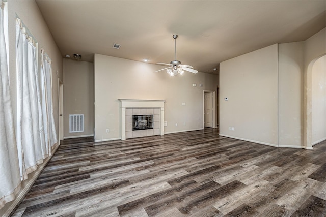 unfurnished living room featuring a ceiling fan, visible vents, wood finished floors, and a fireplace