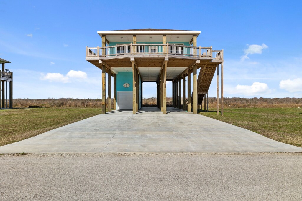 coastal inspired home featuring a carport, concrete driveway, and a front lawn
