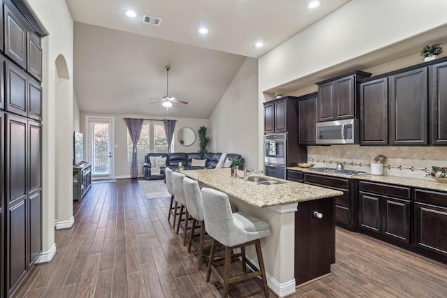 24146 Valencia Ridge Ln, Katy, TX 77494 - kitchen with dark wood-type flooring, a ceiling fan, a kitchen breakfast bar, arched walkways, and appliances with stainless steel finishes
