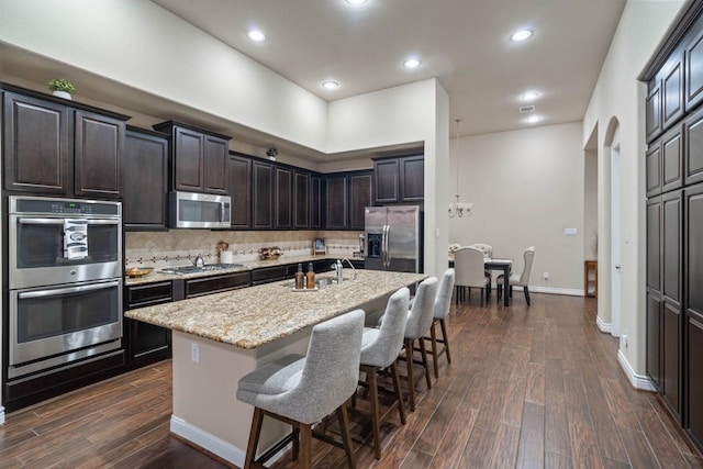 24146 Valencia Ridge Ln, Katy, TX 77494 - kitchen featuring a sink, decorative backsplash, dark wood-type flooring, appliances with stainless steel finishes, and a kitchen bar