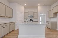 416 Bryan Way, Angleton, TX 77515 - kitchen featuring stainless steel microwave, light countertops, recessed lighting, a center island with sink, and light wood-style flooring