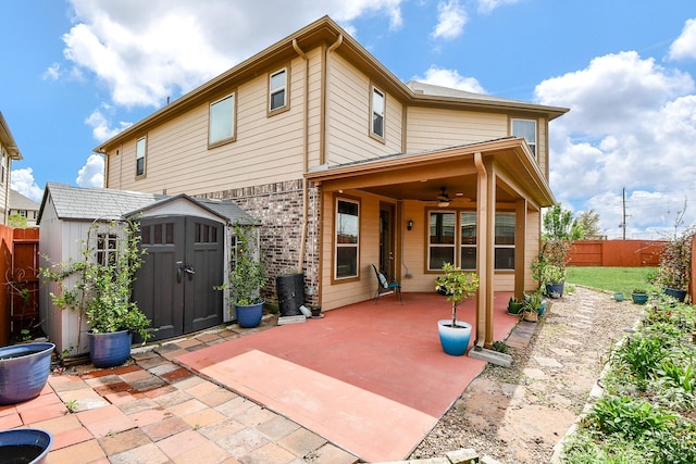 rear view of house featuring a fenced backyard, a shed, a patio area, ceiling fan, and an outbuilding