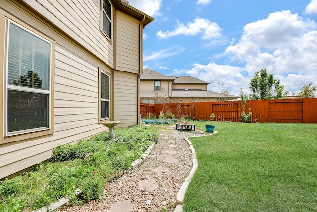 view of yard with a fenced backyard and a fire pit