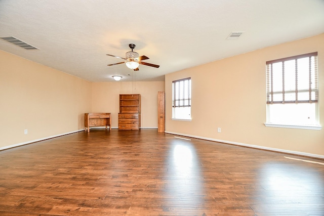 unfurnished room featuring dark wood-type flooring, visible vents, and ceiling fan