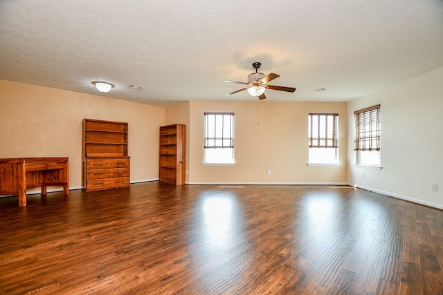 spare room with dark wood finished floors, ceiling fan, baseboards, and visible vents