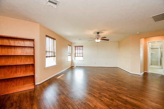 empty room featuring dark wood-type flooring, visible vents, and a ceiling fan