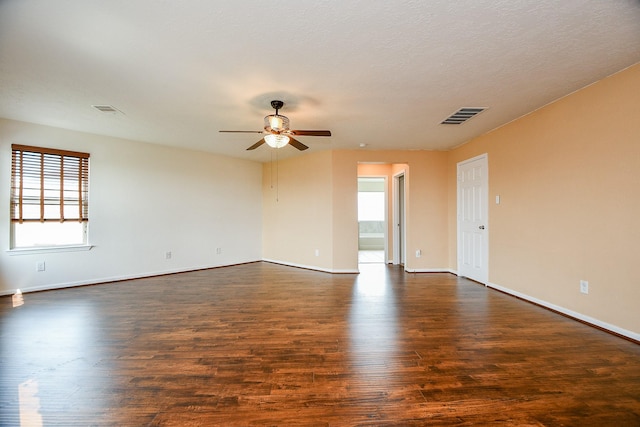 unfurnished room with dark wood-style floors, baseboards, a ceiling fan, and visible vents