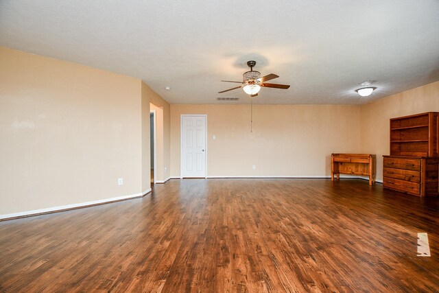 spare room featuring baseboards, visible vents, a ceiling fan, and dark wood-style floors