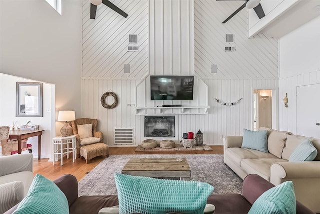 23155 Gulf Dr, Galveston, TX 77554 - living area with beam ceiling, a glass covered fireplace, wood finished floors, a towering ceiling, and ceiling fan