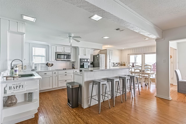 23155 Gulf Dr, Galveston, TX 77554 - kitchen featuring a kitchen bar, a ceiling fan, a sink, a center island, and appliances with stainless steel finishes