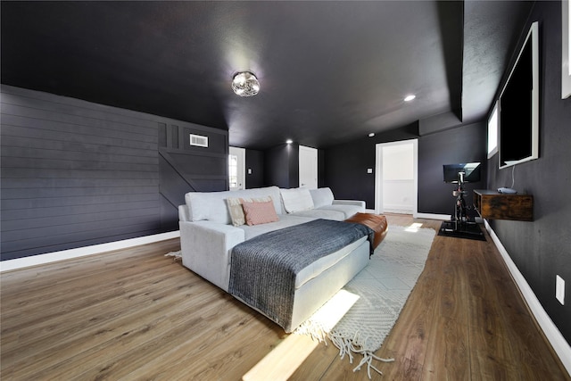 bedroom with visible vents, baseboards, wood finished floors, and lofted ceiling