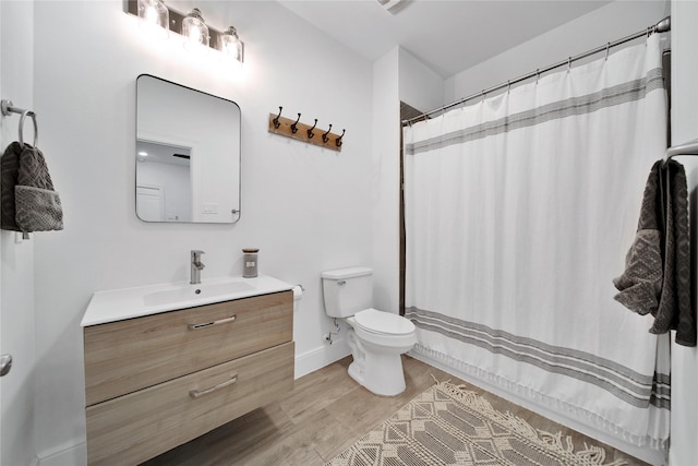 bathroom featuring vanity, baseboards, curtained shower, toilet, and wood finished floors