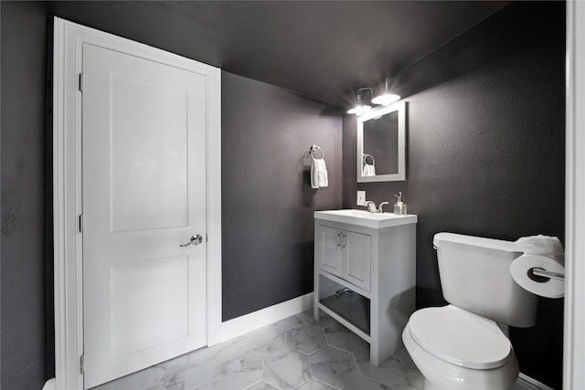 bathroom featuring toilet, marble finish floor, baseboards, and vanity