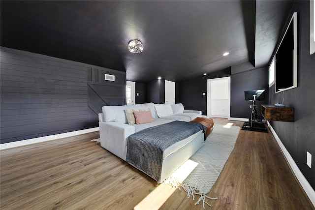 bedroom featuring visible vents, baseboards, vaulted ceiling, and wood finished floors
