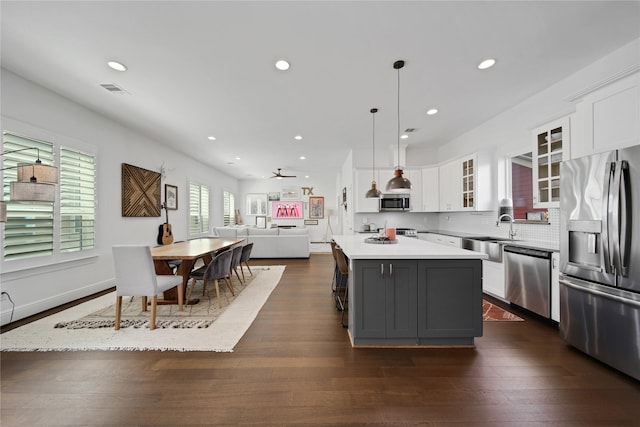kitchen featuring white cabinets, light countertops, a sink, stainless steel appliances, and open floor plan