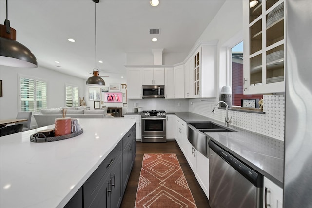 kitchen featuring visible vents, white cabinets, glass insert cabinets, a sink, and stainless steel appliances