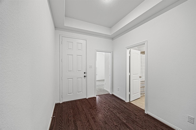 foyer featuring a raised ceiling, baseboards, and wood finished floors