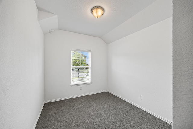 unfurnished room featuring baseboards, dark colored carpet, and vaulted ceiling