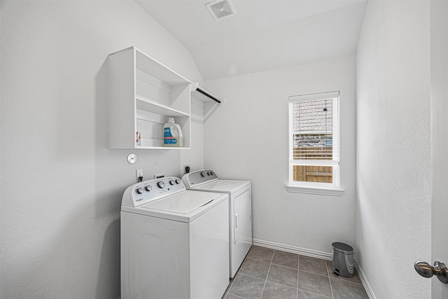 washroom featuring laundry area, separate washer and dryer, visible vents, light tile patterned flooring, and baseboards