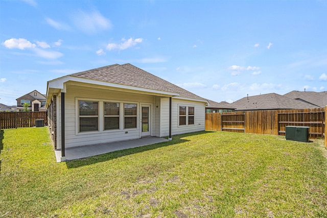 rear view of property featuring roof with shingles, a yard, a patio, and a fenced backyard