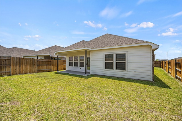 back of property featuring a shingled roof, a fenced backyard, a patio area, and a lawn