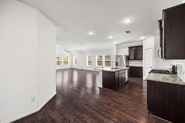 kitchen with stainless steel fridge with ice dispenser, stove, visible vents, and dark brown cabinets