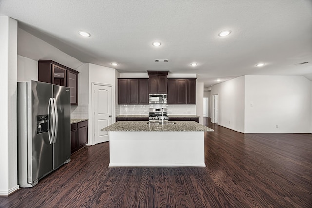kitchen with stainless steel appliances, dark brown cabinetry, dark wood-style floors, and backsplash
