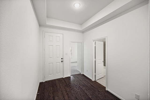 foyer entrance with a tray ceiling, baseboards, and wood finished floors