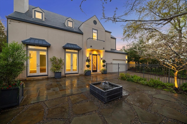 3126 Mid Ln, Houston, TX 77027 - view of front of house featuring french doors, a chimney, a standing seam roof, a metal roof, and stucco siding
