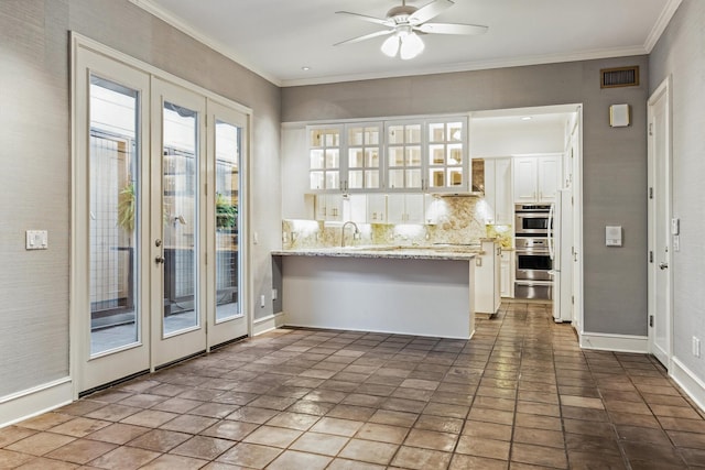 3126 Mid Ln, Houston, TX 77027 - kitchen with white cabinetry, ceiling fan, a warming drawer, a peninsula, and ornamental molding