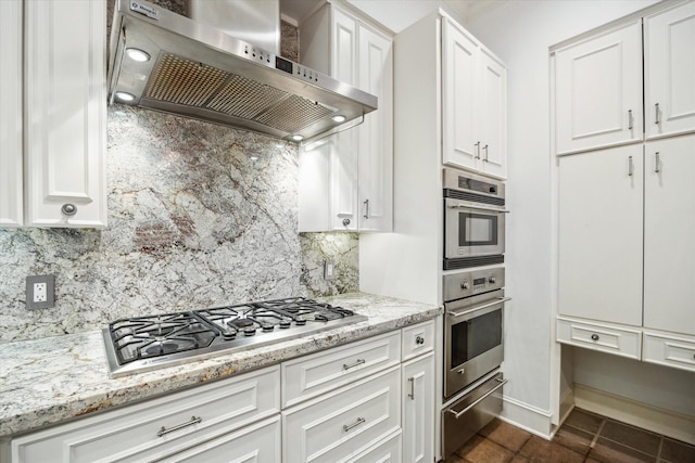 3126 Mid Ln, Houston, TX 77027 - kitchen with wall chimney range hood, appliances with stainless steel finishes, white cabinets, light stone countertops, and backsplash
