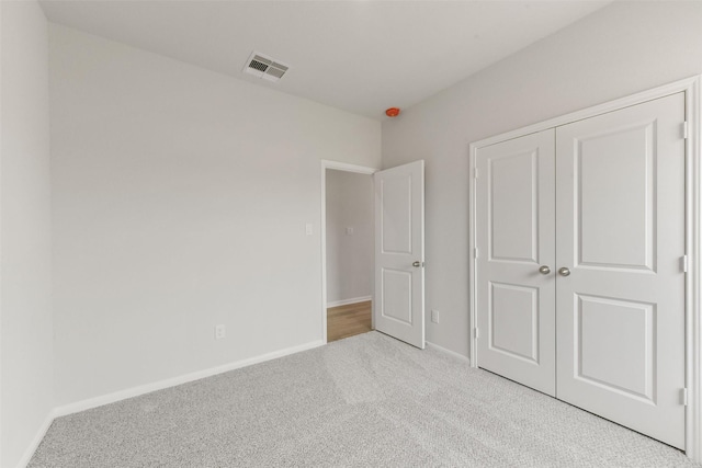 unfurnished bedroom with a closet, visible vents, carpet flooring, and baseboards