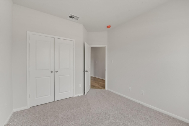 unfurnished bedroom with a closet, visible vents, carpet flooring, and baseboards