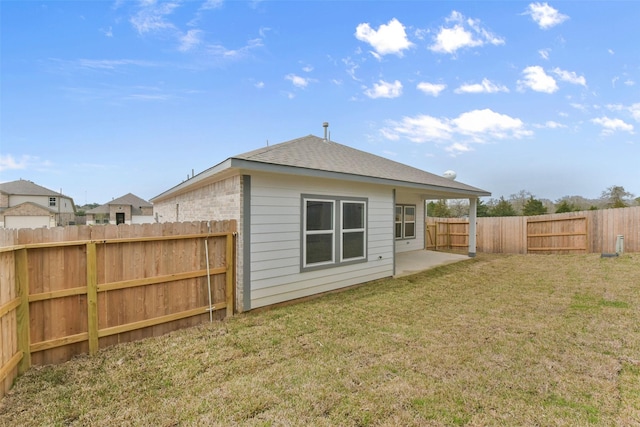 back of property with a patio area, a yard, a fenced backyard, and a shingled roof