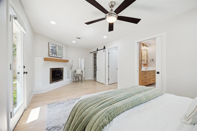 3427 Linkwood Dr, Houston, TX 77025 - bedroom with a barn door, light wood-style floors, recessed lighting, a fireplace, and baseboards