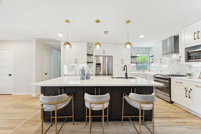 3427 Linkwood Dr, Houston, TX 77025 - kitchen featuring appliances with stainless steel finishes, a sink, wall chimney exhaust hood, light wood-type flooring, and tasteful backsplash