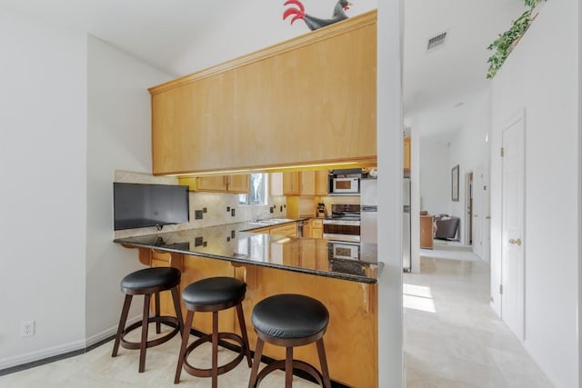 kitchen featuring white appliances, backsplash, a sink, and a kitchen bar