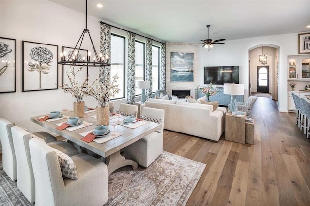 living area with ceiling fan, arched walkways, a fireplace, wood finished floors, and recessed lighting