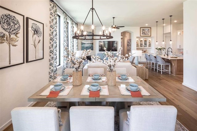 dining area featuring an inviting chandelier, arched walkways, recessed lighting, and wood finished floors