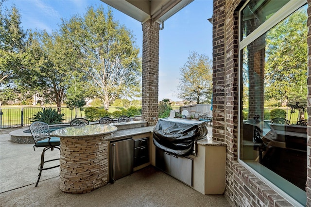 view of patio / terrace featuring area for grilling, outdoor wet bar, fence, and exterior kitchen