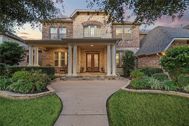 doorway to property featuring a porch, stone siding, and brick siding