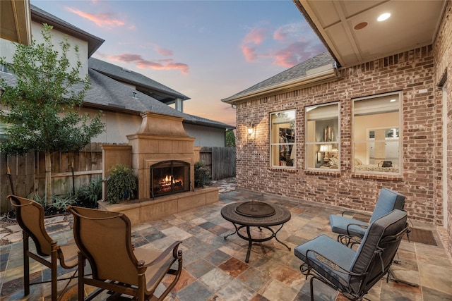 patio terrace at dusk with fence and a tile fireplace