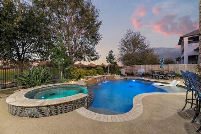 pool at dusk with a patio area, a pool with connected hot tub, and a fenced backyard