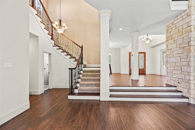 foyer entrance featuring wood finished floors, an inviting chandelier, baseboards, and stairs