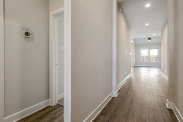 hallway featuring recessed lighting, baseboards, and dark wood-style flooring