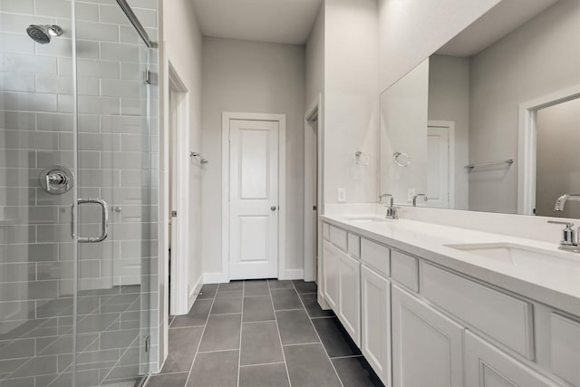 bathroom featuring tile patterned floors, a stall shower, double vanity, and a sink